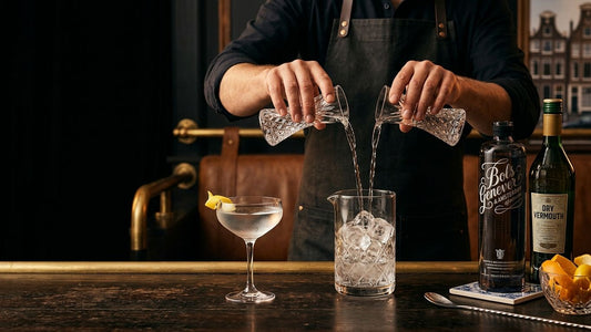 Bartender stirring equal parts gin and vermouth with ice to prepare a classic 50/50 martini in crystal glasses