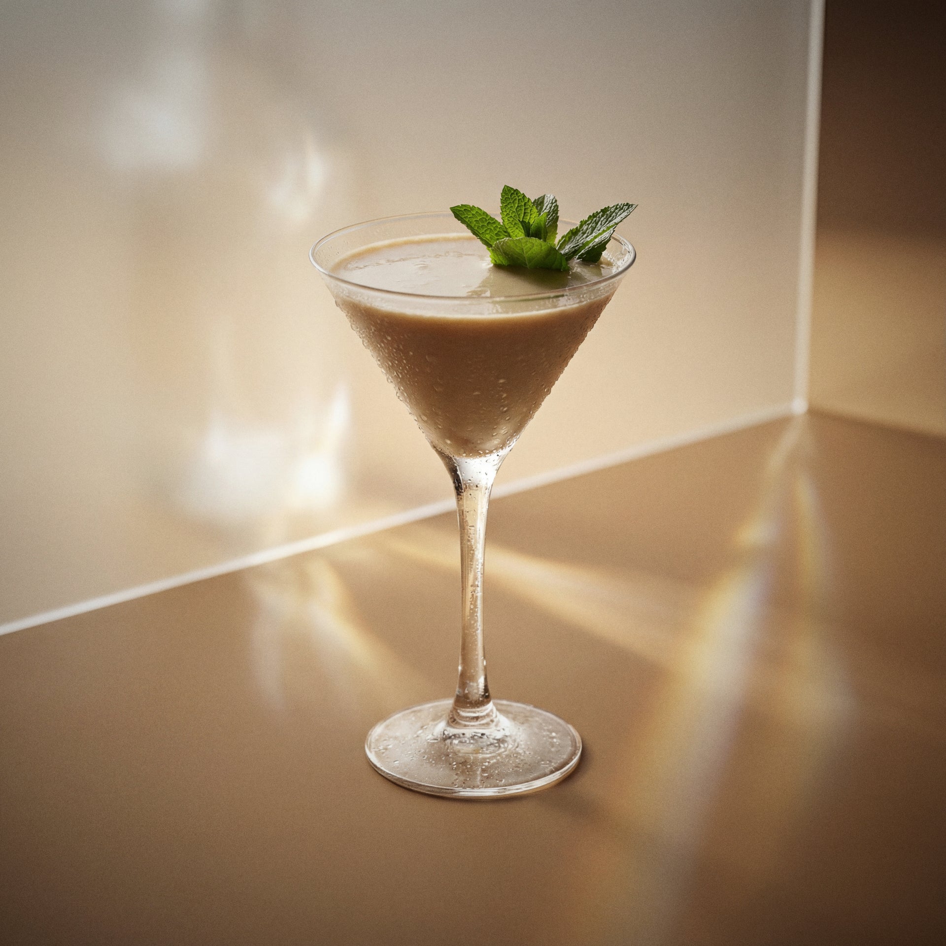 after eight cocktail with brown cream liqueur, cacao brown liqueur, and vodka, in a martini glass with a mint sprig on a reflective surface.