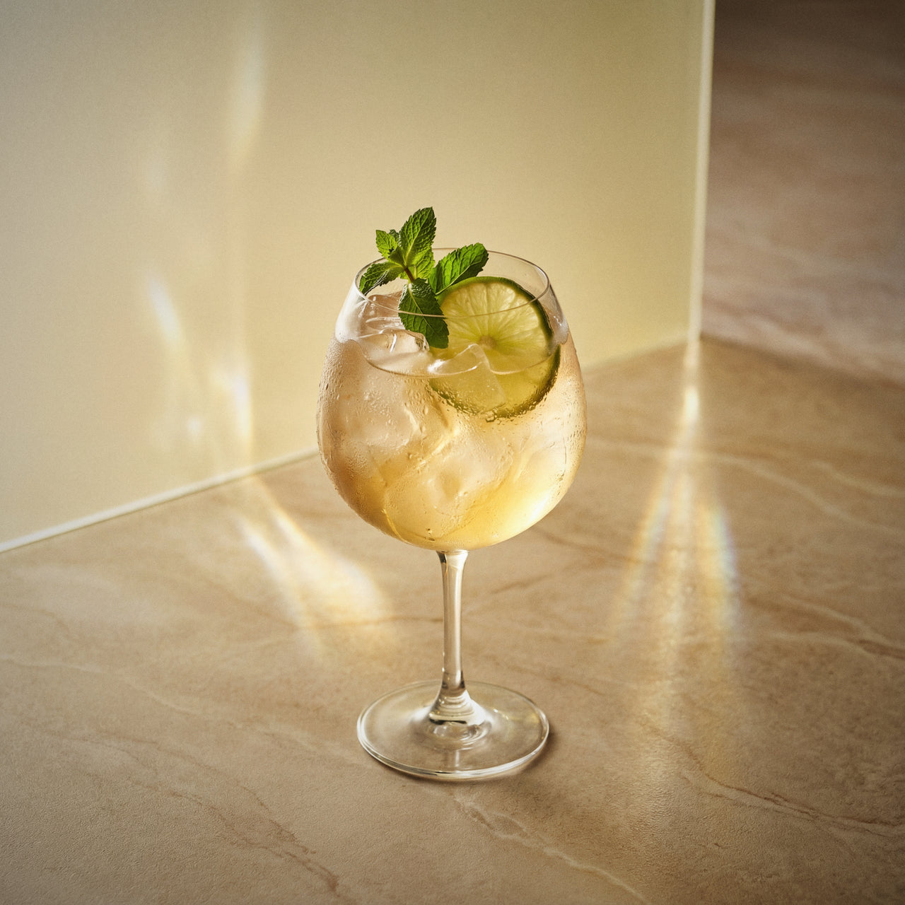 banana spritz cocktail with lime and mint in a coppa glass on a marble surface
