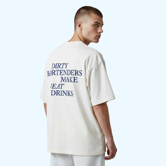 A man wearing an oversized off-white t-shirt with blue text on the back reading 'DIRTY BARTENDERS MAKE NEAT DRINKS', 