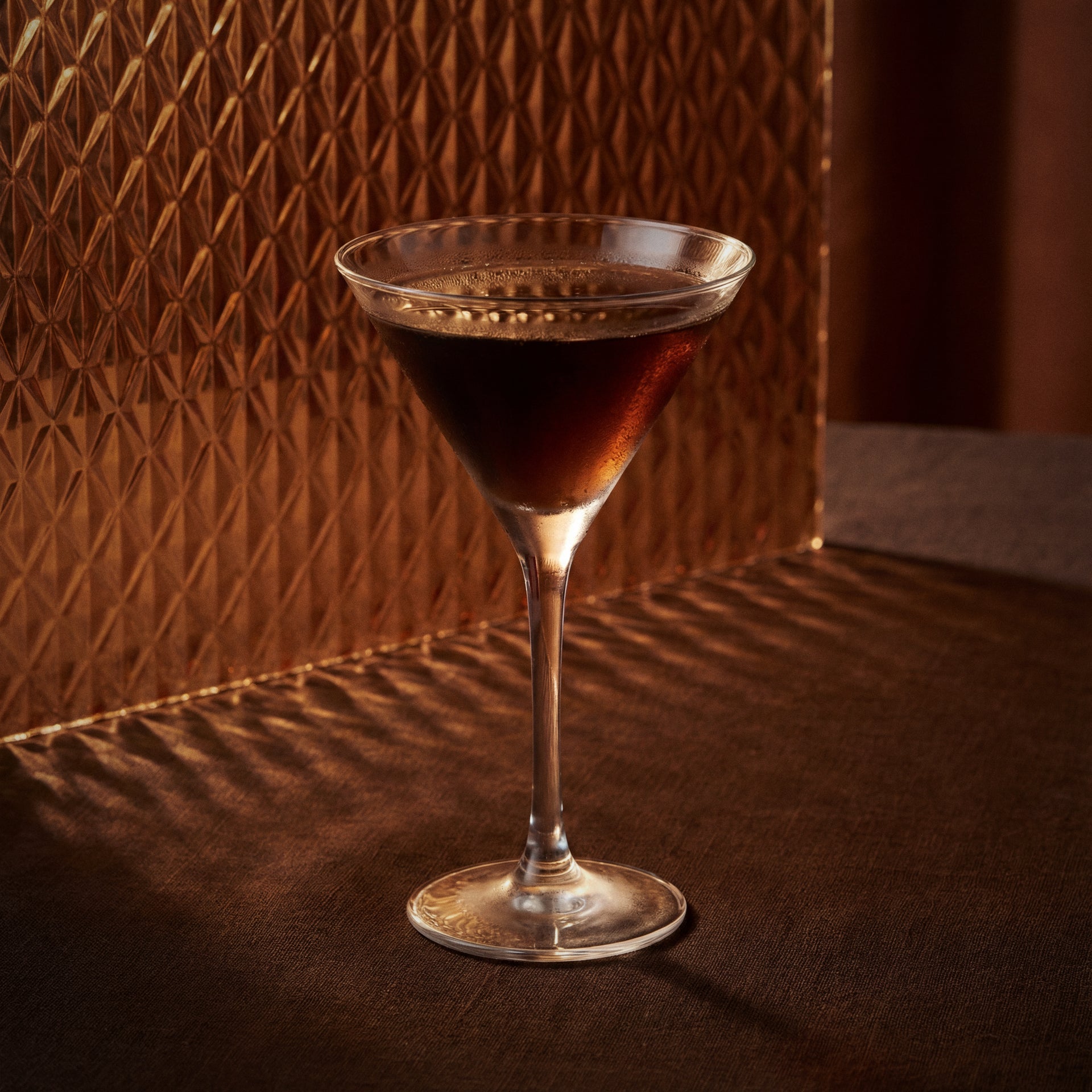 black martini cocktail with cacao brown liqueur in a martini glass on a textured surface