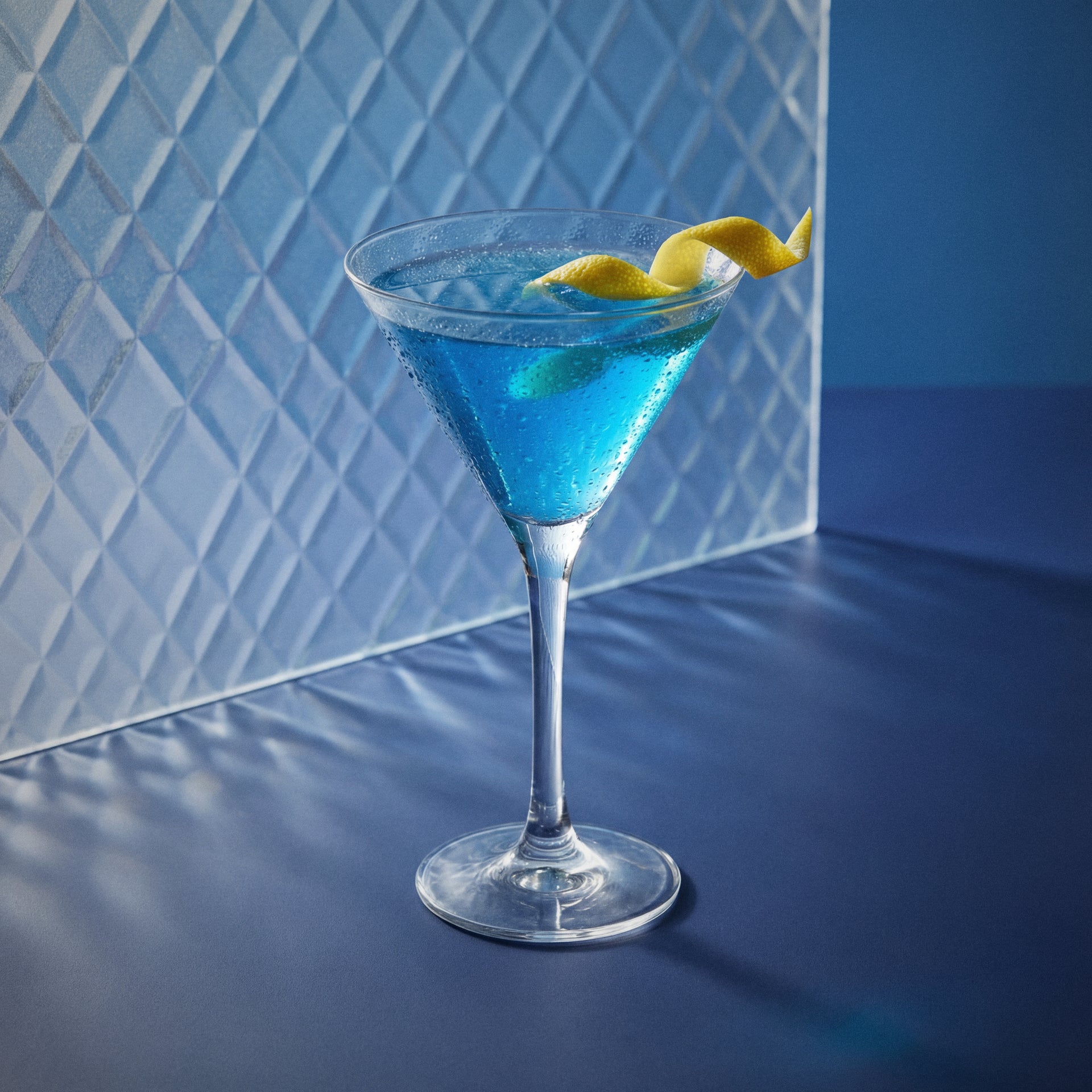 blue lady cocktail with blue liqueur and gin in a martini glass with a lemon twist on a textured background