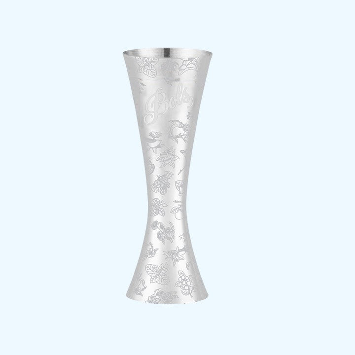 A silver metal jigger with an engraved floral and bird pattern and the brand name 'Bella' on the side, set against a solid light blue background.