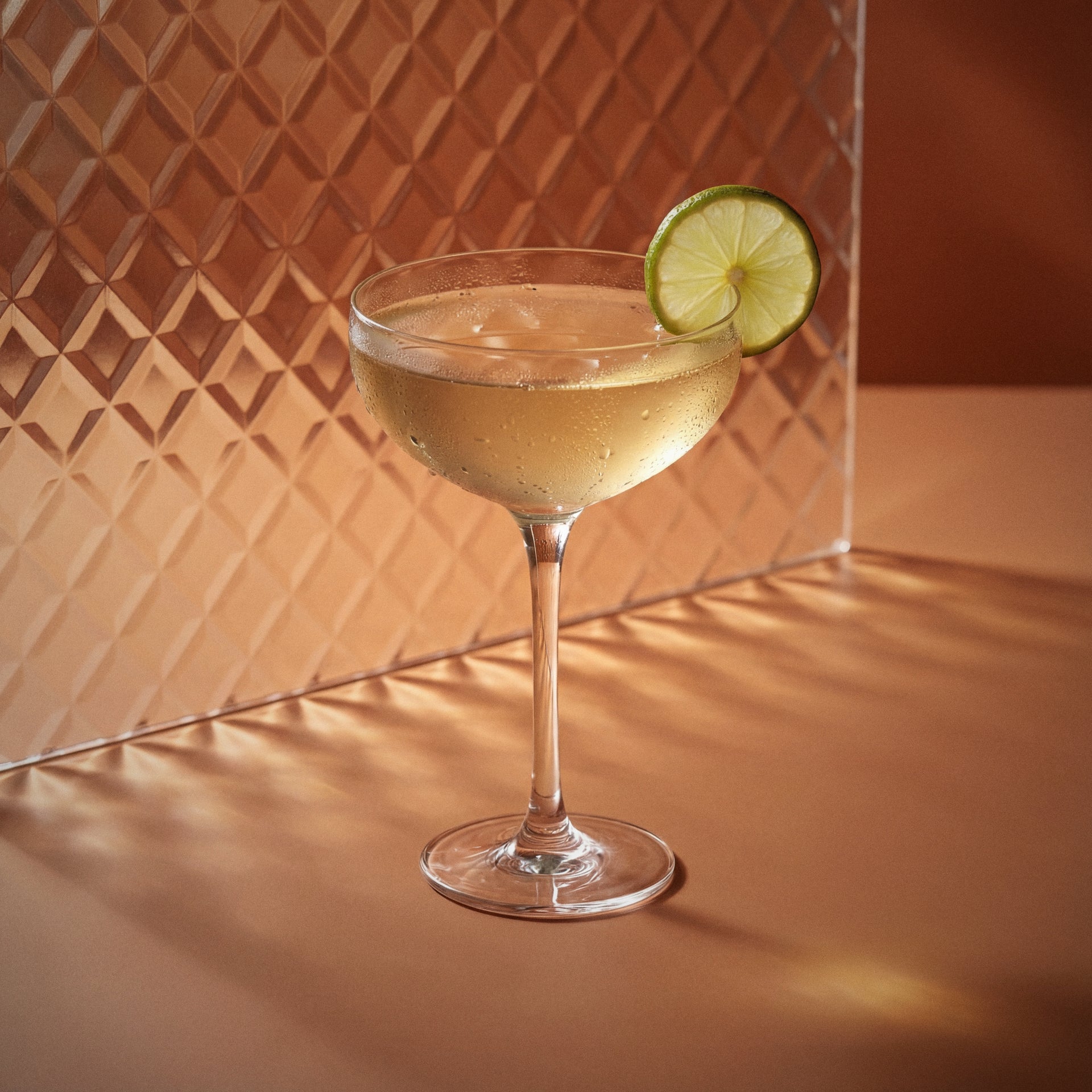 butterscotch daiquiri cocktail with butterscotch liqueur in a coupe glass with a lime wheel on a textured surface
