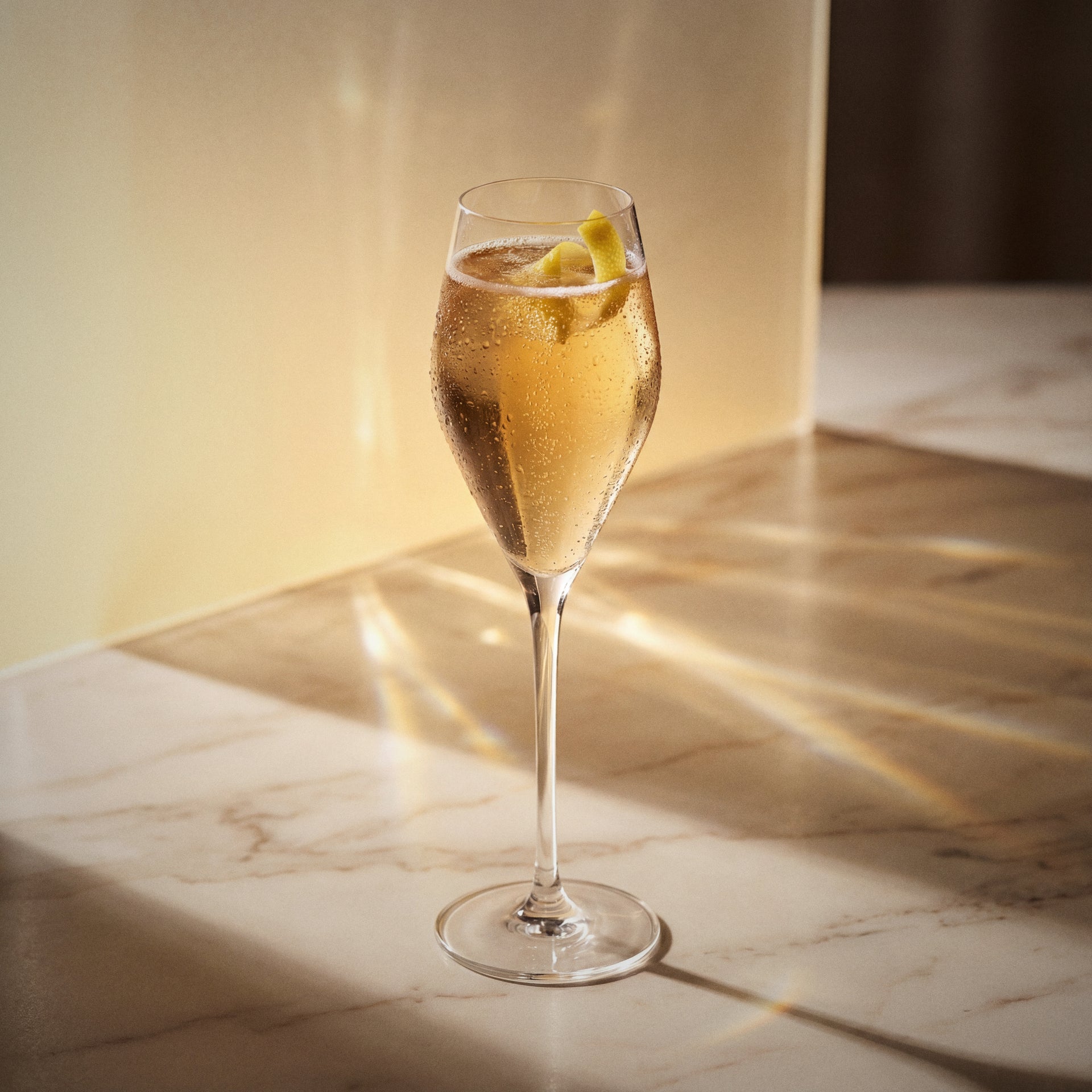 elderflower royale cocktail with elderflower liqueur in a flute glass with bubbles on a marble surface