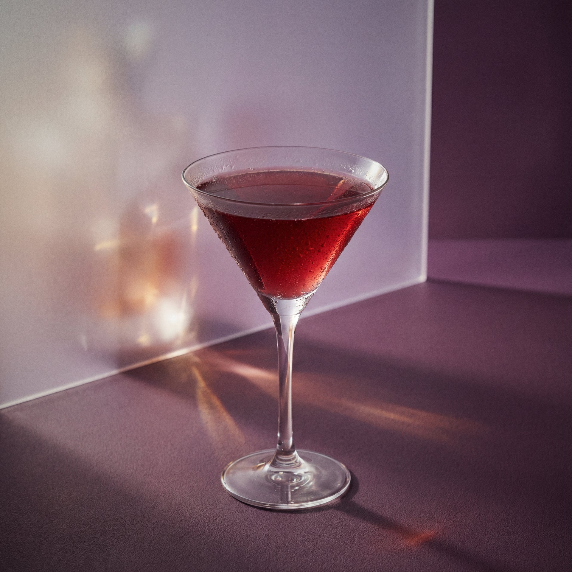 english rose cocktail with parfait amour liqueur and gin in a martini glass on a textured surface