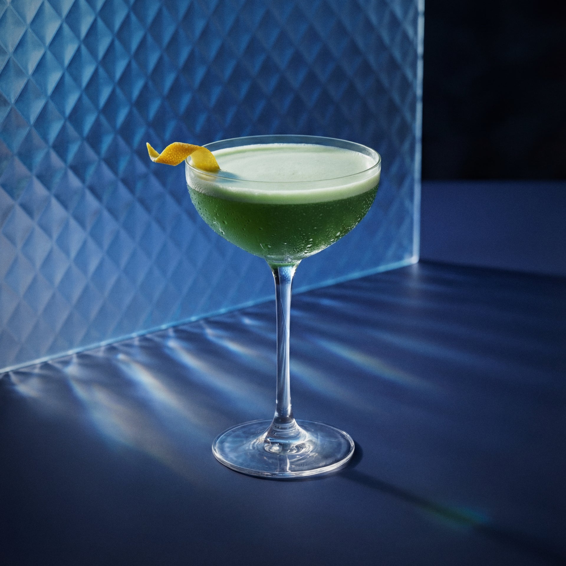 island espresso martini cocktail with blue 1575 liqueur and vodka in a coupe glass with a orange twist garnish on a blue background