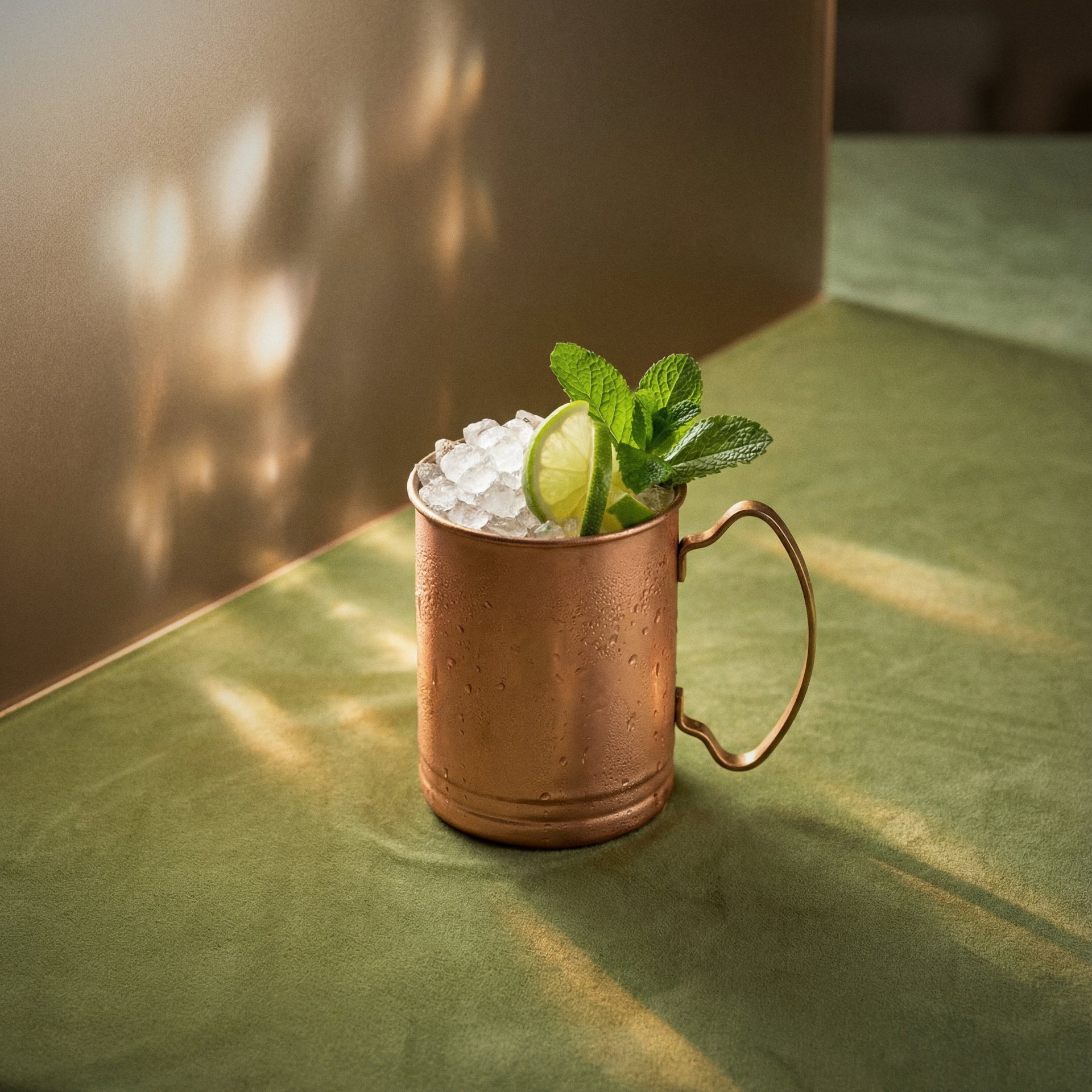 kiwi mule cocktail with kiwi liqueur in a copper mug with a lime wheel and mint as garnish on a textured surface 