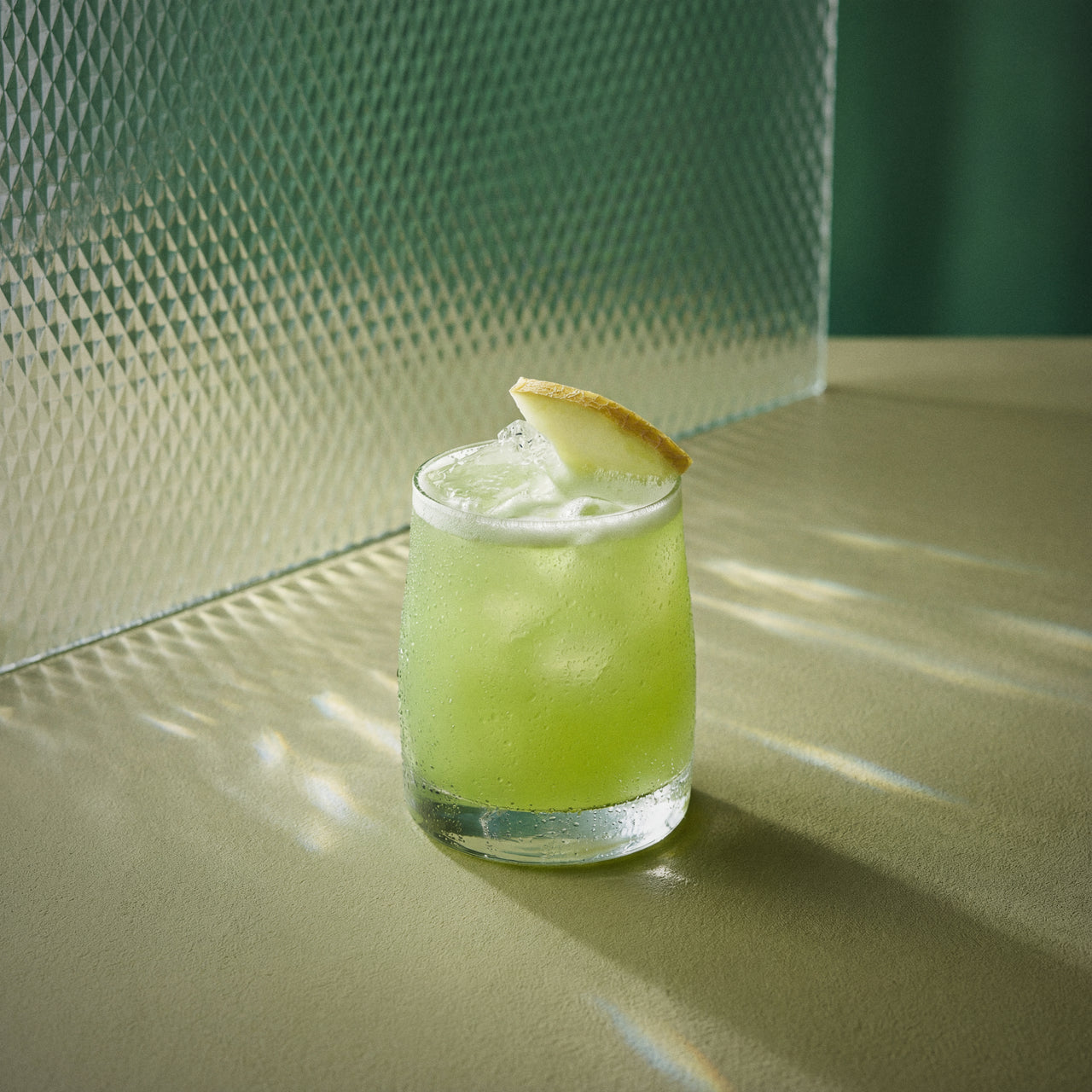 melon sour cocktail with melon liqueur and a melon twist on a textured surface