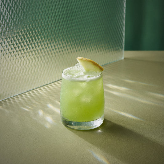 melon sour cocktail with melon liqueur and a melon twist on a textured surface