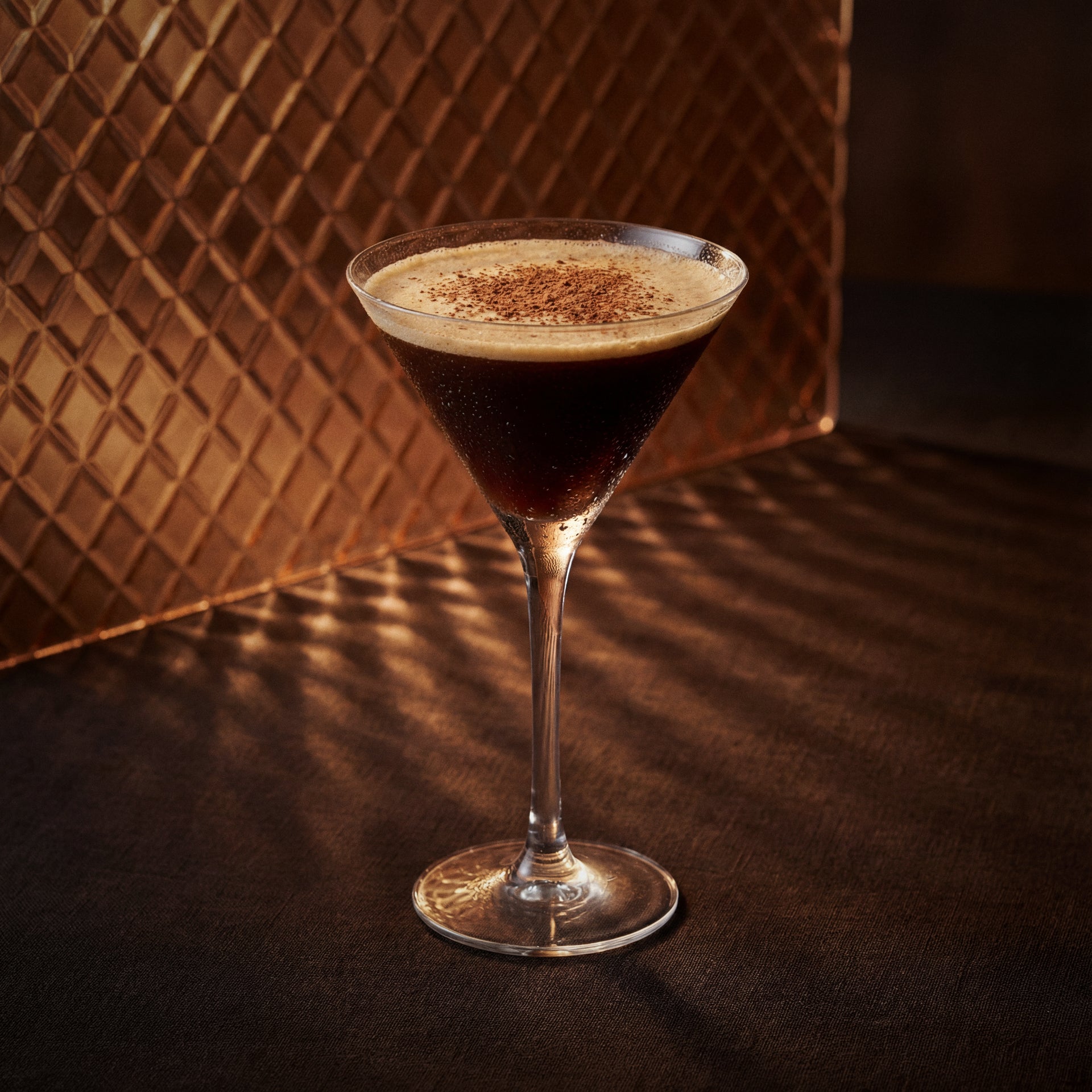 moca cocktail in a martini glass with cacao powder made with cacao brown liqueur and in a glass brown surface