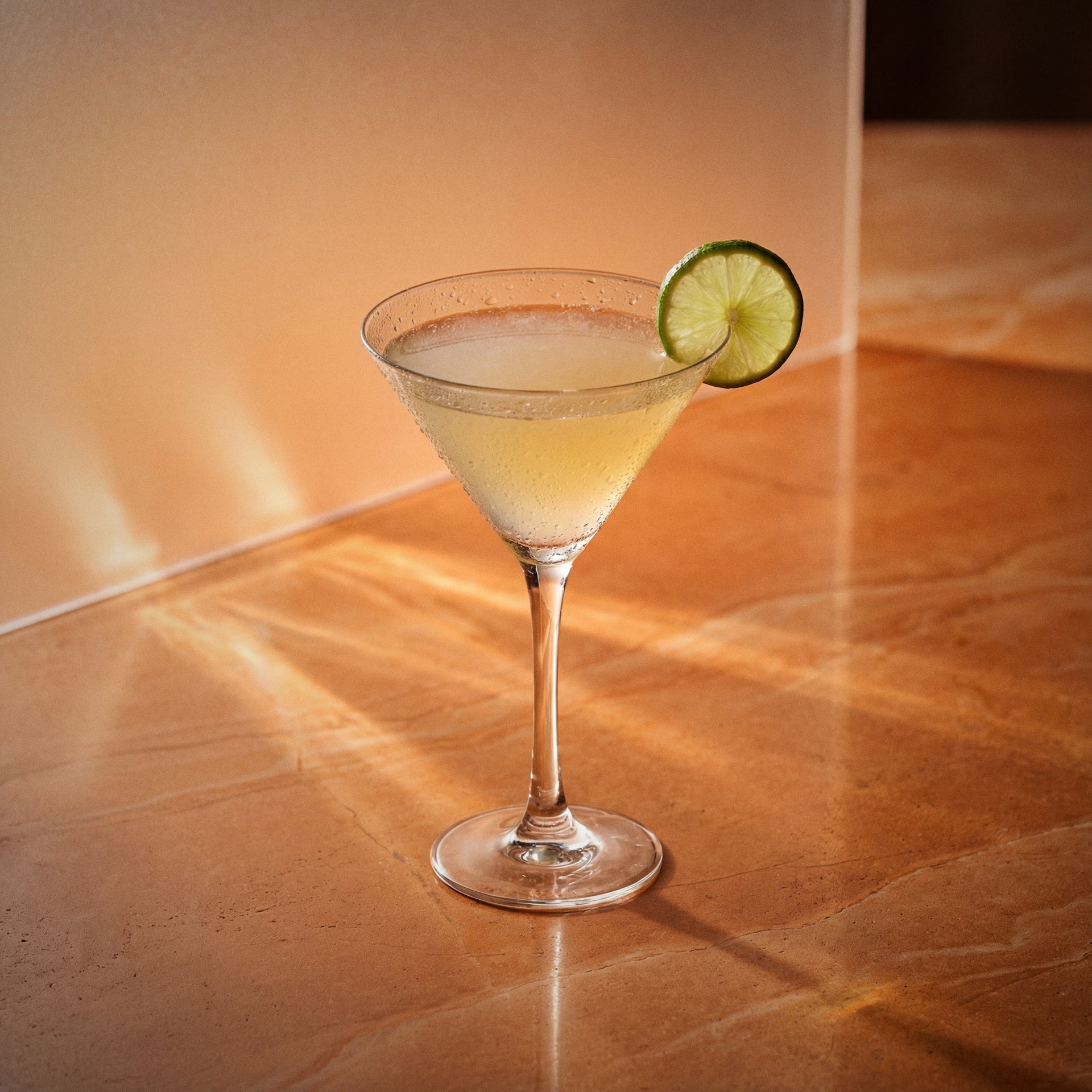 nacional daiquiri cocktail with apricot brandy liqueur in a martini glass and a lime wheel as garnish on a yellow surface