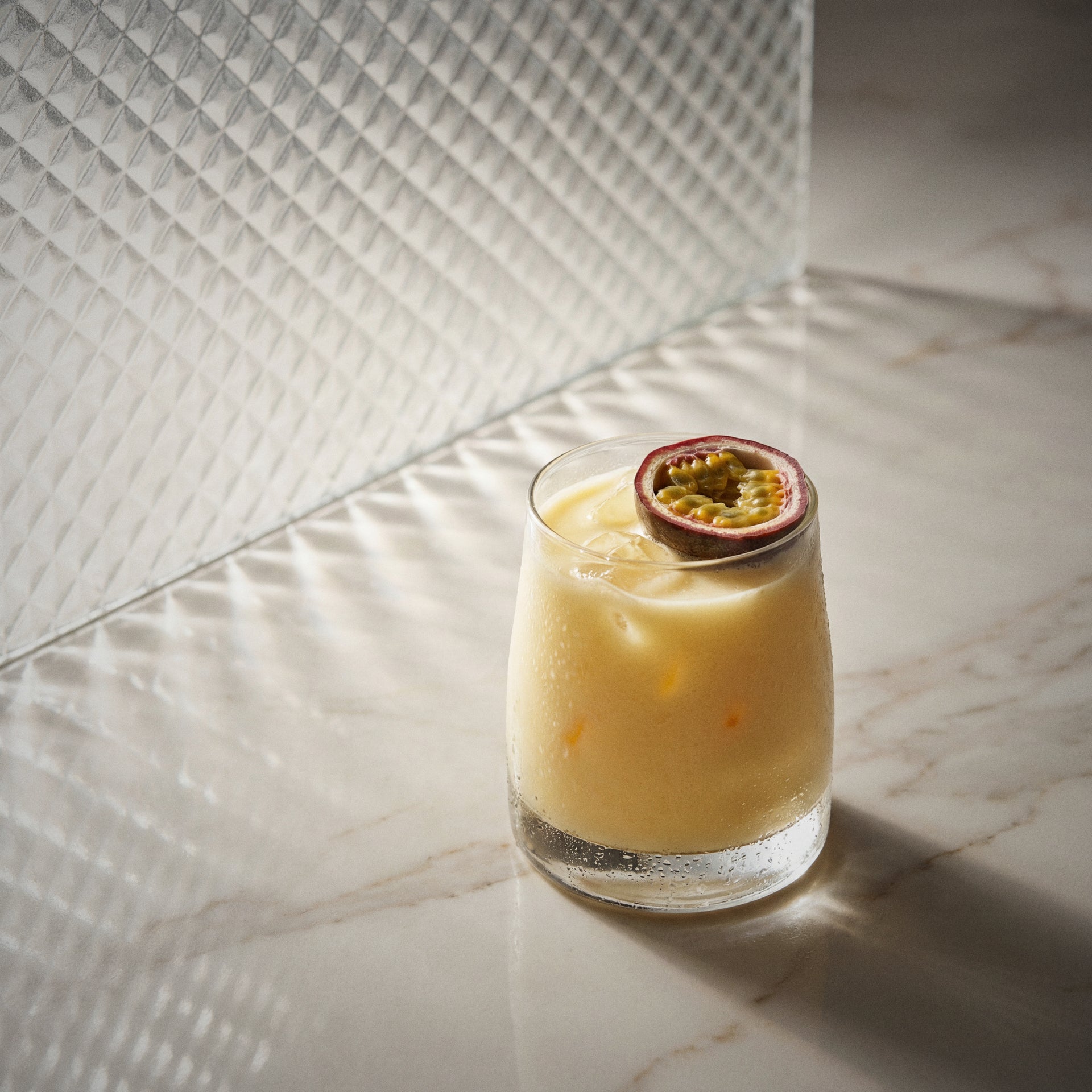 passion natural yoghurt cocktail with natural yoghurt liqueur and with a passion fruit slice on a marble surface