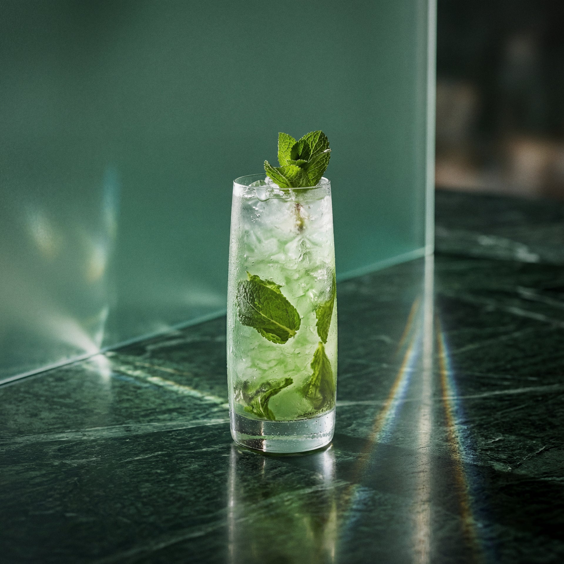 peppermint green mojito cocktail with mint and peppermint liqueur in a highball glass on a reflective surface