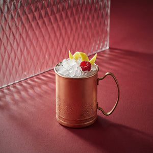 raspberry mule cocktail with raspberry liqueur in a copper mug on a red surface
