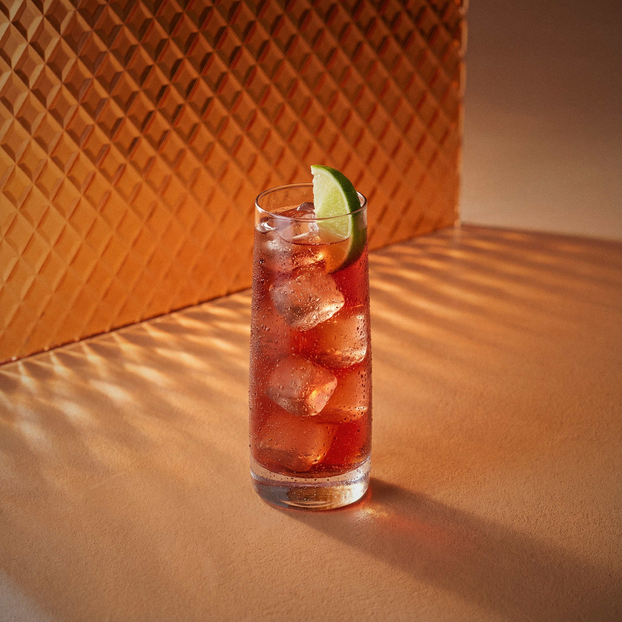 Woo Woo cocktail in a highball glass with a lime wedge and peach liqueur on a textured surface