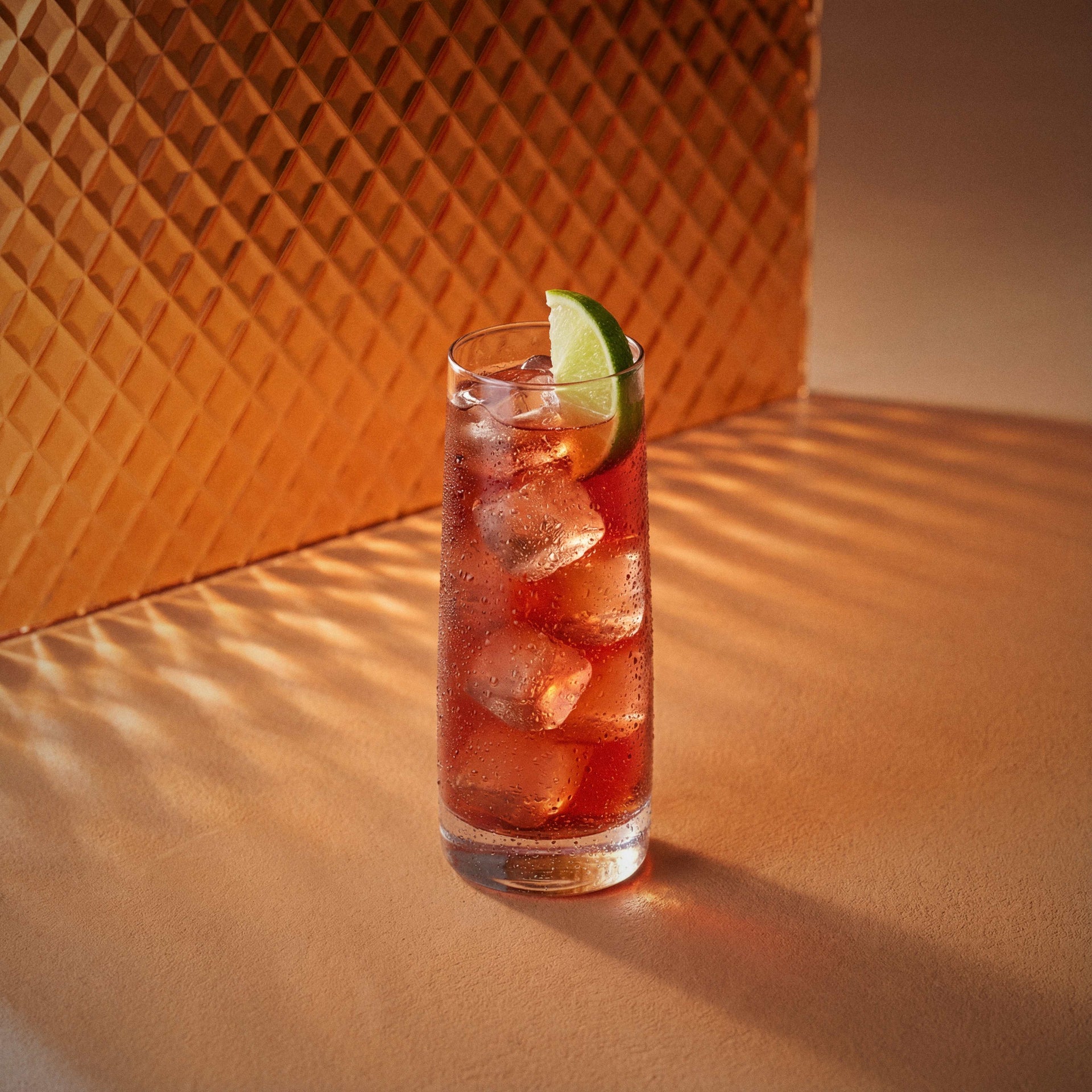 Woo Woo cocktail in a highball glass with a lime wedge and peach liqueur on a textured surface