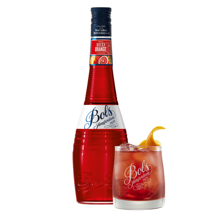 A bottle of Bols Red Orange liqueur next to a glass of cocktail, garnished with an orange slice.